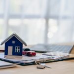 Mini casa, apoiada em materiais de escritório sob uma mesa.