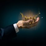 Imagem de uma mão segurando moedas de ouro e gráficos financeiros ascendentes, simbolizando gestão patrimonial, crescimento financeiro e investimentos, ideal para conteúdo de finanças e economia.